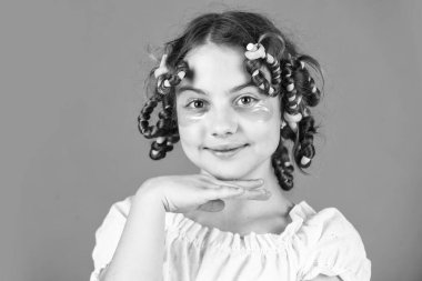 Mükemmel görünüyor. Kuaförde oynayan, saç bigudili mutlu kız. Çocuklar için saç stili yapmak için kolay ipuçları. Kuaför aletleri ve saç aksesuarları. Yüzü yamalı çocuk. Saç bigudileriyle poz ver