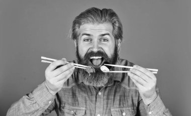 hipster yemek çubuklarıyla suşi yer. Lezzetli suşi rulosu. Japonya 'da geleneksel ve sağlıklı yiyecekler. Japon suşi yemeği. Geleneksel Japon yemeklerini çubuklarla yiyen adam. Akşam yemeği evde..