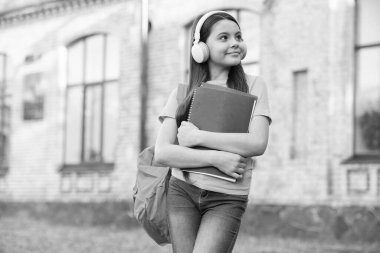 En sevdiği melodi. Okula dönüyorum. Genç kız, sesli kitabı dinle. Okul bahçesinde defteri olan bir çocuk. Mutlu çocuk klasörü tutuyor. Küçük kız dışarıda kulaklık takıyor. Modern hayatta okul eğitimi