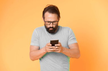 Hippi kafası karışmış, akıllı telefon kullanıyor. Modern akıllı telefonun tecrübesiz kullanıcısı. Akıllı telefonla irtibatta kal. Çevrimiçi topluluğa katıl. Kullanıcı dostu kavram. Adam cep telefonu fırsatlarını şaşırttı