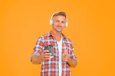 Mutlu modern adam, kahve fincanının reklamını ve sarı arka planının reklamını yapıyor.