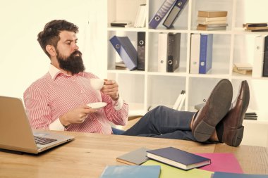 Sakallı adam ofis masasında çay ya da kahve içmeyi sever.