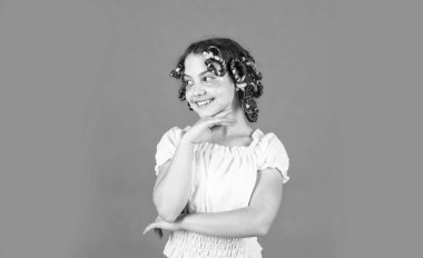 Çocuk saç stili yapıyor. Saçları bukleli küçük mutlu kız. Güzellik için göz altı kumaş maskesi. Gözlerinin altında yamalar olan sevimli bir çocuk. Çocuk manken konsepti. Örgülü kıvırcık saçlı..