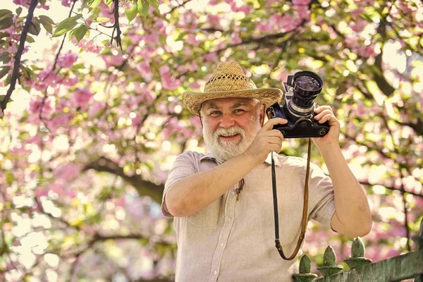 Travel and tourism. Spring holidays. Travel photo. Retirement travel. Capturing beauty. Photographer in blooming garden. Senior man hold professional camera. Photography courses. Happy grandfather