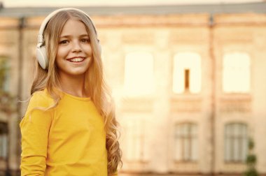 Müzik kanalı. Çocuk modern teknolojiyi kullanıyor. Ruh için müzik. Modern çocuk. Müzik dinleyen kız, modern alet. Kablosuz kulaklıkla mutlu bir çocuk. Gün batımında şehir arka planında. Stereo kulaklıklar
