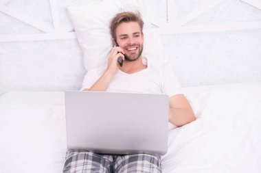 Konuşmanın tadını çıkar. Mutlu adam yatakta cep telefonuyla konuşuyor. Telefon var. Telefon var.