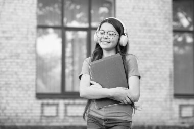 Kızlar dünyayı hak ediyor. Bilgiyi kitaptan al. Modern okul eğitimi. Okula dönüyorum. Mutlu gençler ders kitabı taşır. Gülümseyen çocuk klasörleri tutuyor. çocukluk mutluluğu. Kulaklıklı kız müzik dinliyor.