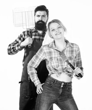 Birlikte yemek pişirmek. Tam bir barbekü tabağı. Sakallı hippi ve kız ızgara çatal bıçaklarını beyaz arka planda tutuyorlar. Piknik ve barbekü. Aile barbeküye hazırlanıyor. Barbekü tekniği