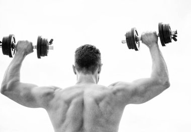 Eylemler koçlardan daha yüksek sesle konuşur. Sırtı ve kolları güçlü bir sporcu. Spor malzemeleri. Vücut geliştirme sporu. Spor yaşam tarzı. Aptal egzersiz salonu. Dambıl gibi arkadan bakan kaslı bir adam.