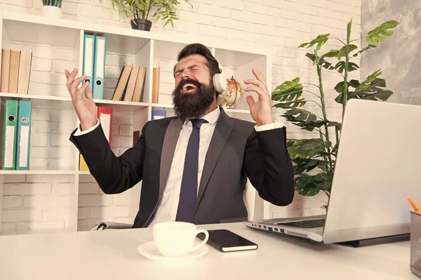 Music for stress relief. Businessman enjoy music in office. Bearded man listen to music and sing along to song. Relaxing music for work. Modern life. New technology
