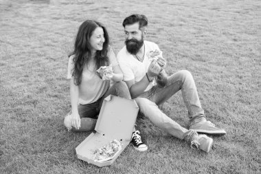 Boş vakit geçirmek için. fast food. Sakallı hippi adam ve sevimli kız pizza yiyorlar. Yeşil çimlerde yaz pikniği. Diyet olsun. Birbirine aşık çiftler. Açlık. Aile hafta sonu. Pizza yiyen mutlu çift. Sağlıklı yemek.