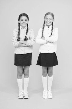 Sonunda mezun oldum. Bilgi günü. çocukluk mutluluğu. Sarı arka plandaki akıllı küçük kızlar. Eğitim konsepti. Okula dönüyorum. Okul üniformalı kızlar. Çocuk modası. Arkadaşlık ve kardeşlik.