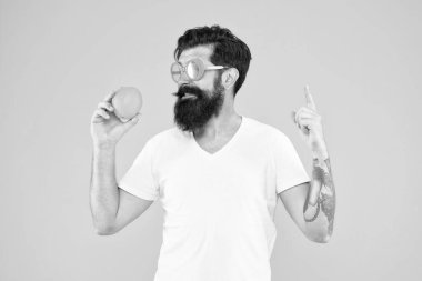 Tazeleme kaynağı. Yaz beslenmesi. Yaz havasında sakallı hippi. Neşeli adam olgun turuncu turunçgil meyvesi tutuyor. Yaz tatili. Sarı arka planda turuncu güneş gözlüklü sakallı hippi.