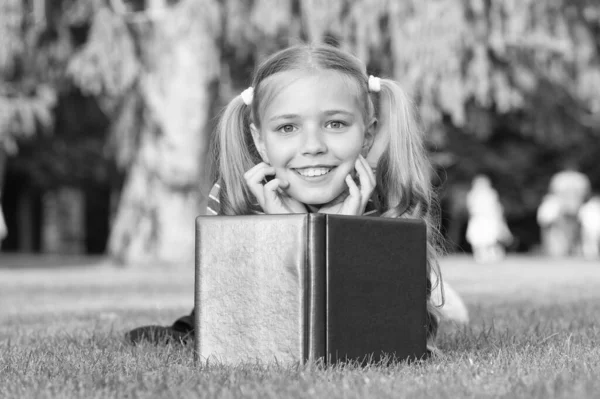 Mix of fantasy and reality. Happy girl read fantasy book on green grass. Little child enjoy fantasy story. Concept of fantasy. Imagination and creativity. Leisure time