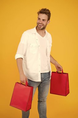 Alışveriş yaparken gülümseyen yakışıklı bir adam. Gerçek alışverişkolik. İnternetten hediyeler ve hediyeler al. Adam alışveriş yapıyor. Çantalı bir tezgahtar. karantina sırasında satın alma