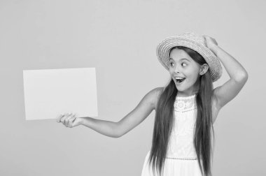 Yeni haberleri paylaşıyoruz. Çocuklar için plaj modası. Sarı arka planda küçük bir çocuk. Yaz kampı aktivitesi. kopyalama alanı. Yaz tatili ve tatil. Mutlu çocukluk. Şaşırmış küçük kız kağıt çarşaf tutuyor.