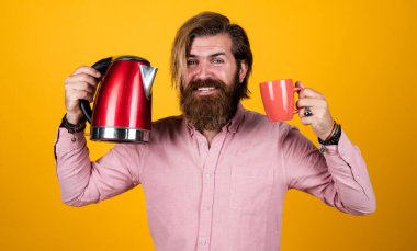 Olgun sakallı adam gündelik moda gibi görünüyor. Çaydanlık, cihaz.