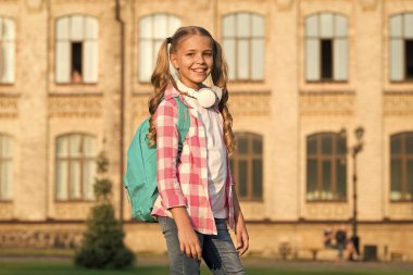 Okul bahçesinde güneşli bir sabah. Mutlu tasasız çocuk. Okul dersleri. Öğrenci. Modern eğitim. Neşeli genç müzik dinliyor. Liseli kız okula gidiyor. Sırt çantalı küçük kız. Okul hayatı