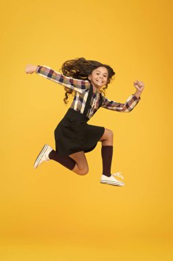 İç enerjiyi hisset. Sarı arka planda atlayan uzun saçlı bir kız. Tasasız çocuk yaz tatili. Eğlence zamanı. Aktif kız özgürlüğü hisseder. Eğlence ve zıpla. Mutlu çocuklar günü. Sıçrama konsepti. İçeri gir