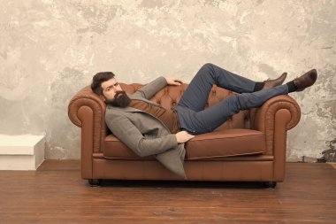 İnsanın kendine güveni böyle olur işte. Sakallı adam kanepede rahatla. İş hayatında kaba bir adam. Moda modası. Moda tarzı. Sakallı ve bıyıklı traşsız bir adam. Berber dükkanı. Kuaför salonu.