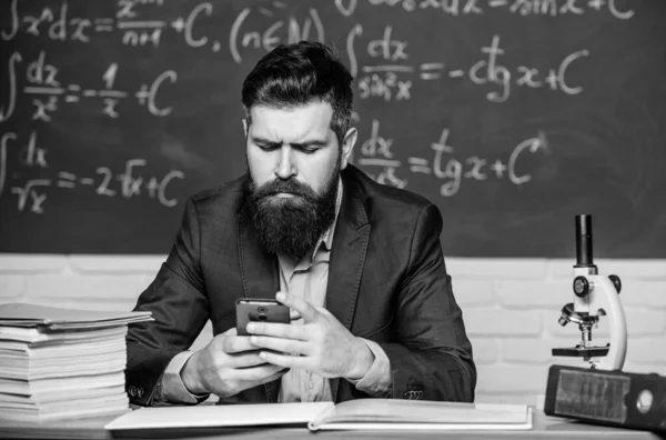 Send message. School application. Study technology. School teacher hold mobile phone chalkboard background. Teacher bearded man learn use modern technology. Learn technology. Modern communication