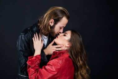 Erkeğe ve kadına aşık şık bir çift deri ceket giyer, öpüşürler.