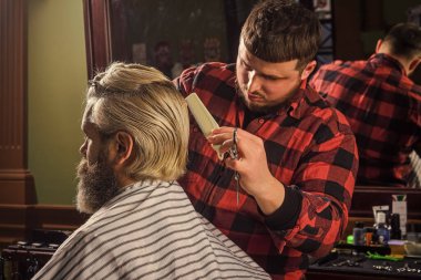 Berber berber dükkanı. Hippi saç tıraşı oluyor. Yüze yakın keskin bir nesne ve kıvranma onu tutan kişinin dikkatini dağıtır. Saç bağışı. Bağış ve yardım konsepti. Sarıya boyanmış saçlı adam. Saç kes.