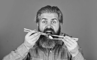 Suşi ruloları. Japon mutfağı. Asya yemeği. Suşi rulosu. Adam suşi çubuğu yiyor. Doğu kültürü. Sakallı hippi rulo yiyor. Japon yemek teslimatı. Suşi ya da sashimi ile servis edilen zencefil turşusu.