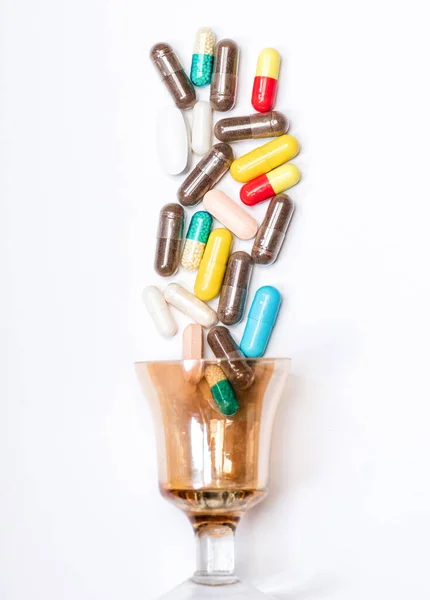 Лекарственные препараты и лекарства. Красочные капсулы проливаются через стекло. Лекарства изолированы на белом — стоковое фото