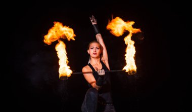 Parıltılı ateş performansı sırasında karanlıkta dönen seksi sanatçı sopaları çeviriyor.