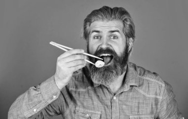 Suşi ruloları. Japon mutfağı. Asya yemeği. Suşi siparişi. Adam evde suşi yiyor. Çubuklu suşi ve zencefil. Doğu kültürü. Sakallı hippi rulo yiyor. Japon yemek servisi.