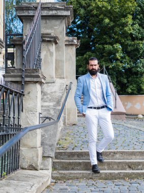 Resmi takım elbiseli, yakışıklı, olgun sakallı bir adam.