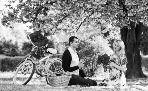 First love. family relationship and friendship. summer holiday trip. girl and man under sakura. couple in love drinking wine during romantic dinner in park. picnic of couple in love at vintage bike