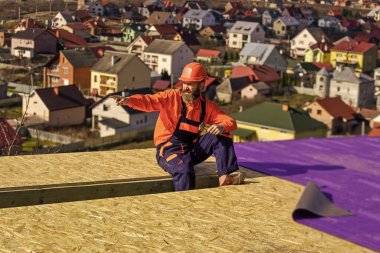 İnşaat becerileri. Çatı ustası güvenlik üniforması denetimi giyer. Çatı tamircisi çalışıyor. Çatı tamircisi. İnşaat endüstrisi ve su geçirmezlik. İnşaat alanındaki binanın çatı yapısında çalışan bir çatı ustası.