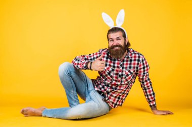 Paskalya avı. Tavşan kulaklı bir adamın portresi. Mutlu Paskalya tatili konsepti. Adam bahar tatilini kutlamaya hazır. Partiye gidiyorum. Komik tavşan kulağı takan sakallı olgun bir adam.