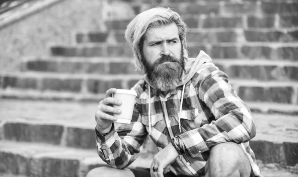 Early morning. Coffee on the go. man with a cup. outdoors. Handsome calm bearded man outdoors with a cup of coffee. Man drinking hot coffee. tourist relaxing on stairs drink tea or coffee