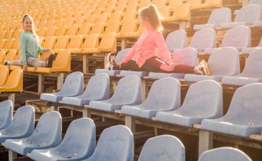 Bacak esnemesi. Genç kızlar stadyum koltuklarında ayrılır. Esneme egzersizleri. Esneme rutini
