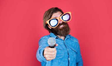 Beyaz tenli sakallı, şık saçlı, sanatsal gözlüklü, mikrofonlu, karaokeli