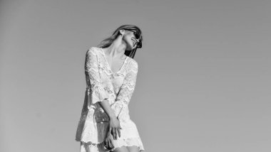 Rahatlamış hissediyorum. Güneş gözlüklü güzel bir kadın. Yazlık kıyafet. Güzel kızın portresi. Plaj tarzı. Yazın açık hava yaşam tarzı. Mavi gökyüzünde poz veren mutlu genç kadın