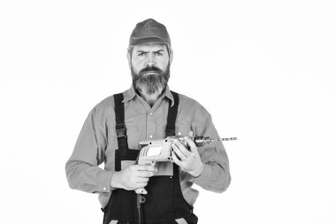 Bir şeye çarpmadan duvarı delmeyi. Beyaz arka planı delinmiş şapkalı bir adam. Tamirci delik açıyor. Güvenlik önlemleri. Sondaj konsepti. Perforatör ve ısırık. Güçlü matkap. Matkap al