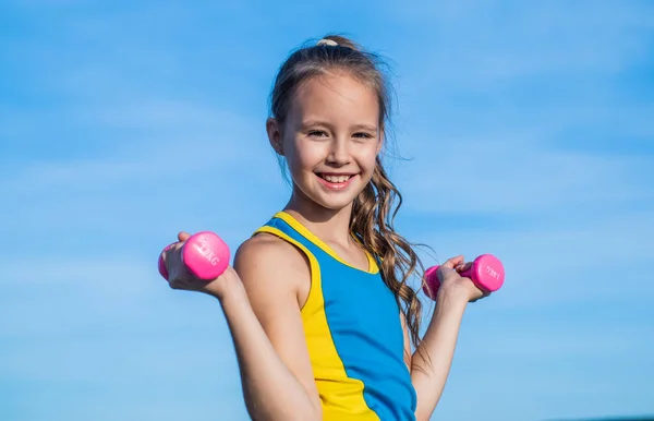 Happy teen girl wear sportswear for training with barbells on sky background, physical training — Stock Photo, Image