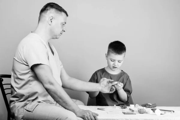 Examen médico. Niño lindo niño y su padre médico. Trabajador del hospital. Servicio médico. Laboratorio de análisis. El pequeño doctor se sienta en la mesa de herramientas médicas. Salud. Concepto de pediatra —  Fotos de Stock