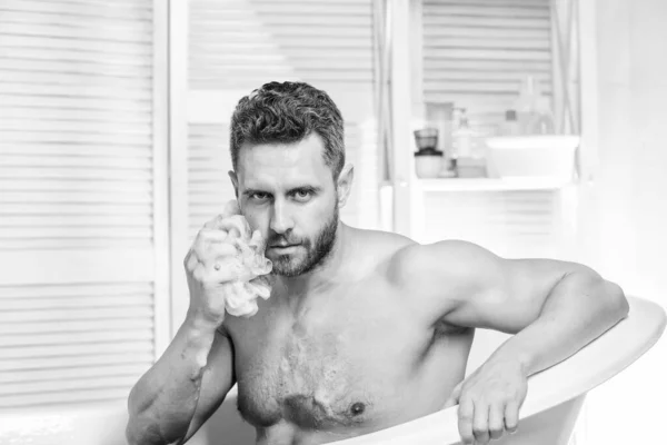 Concept de sexe et relaxation. soins personnels. Homme sexy dans la salle de bain. homme laver le corps musculaire avec mousse éponge. Macho nue dans la baignoire. Laver soigneusement la mousse avec de l'eau. laver son corps. — Photo