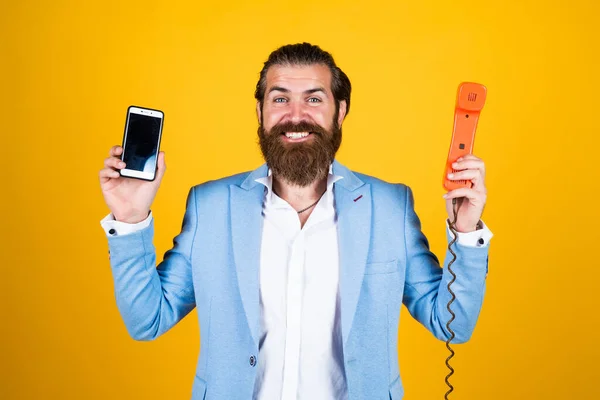 Hombre bien cuidado en la boda formalwear tiene barba uso teléfono retro y teléfono inteligente moderno, la vida moderna —  Fotos de Stock