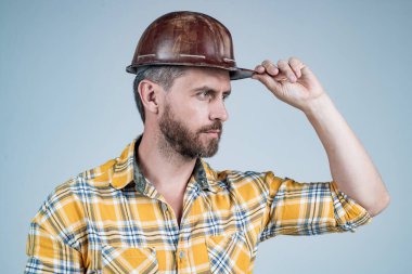 Ciddi görünüşlü bir mimar. Adam işçi üniforması giyiyor. Kasklı yakışıklı inşaatçı..