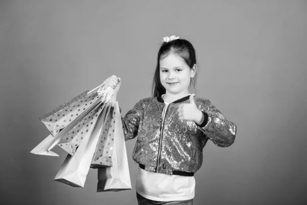Dívka s nákupní tašky fialové pozadí. Nakupování a nákup. Černý pátek. Sleva na prodej. Nákupní den. Dítě drží balíky. Dětská móda. Překvapivý dárek. Skvělé obchody. Skvělá volba — Stock fotografie