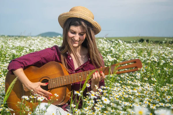 Boldog nő gyűjteni virágok nyáron százszorszép mező játszani akusztikus gitár, vidék — Stock Fotó