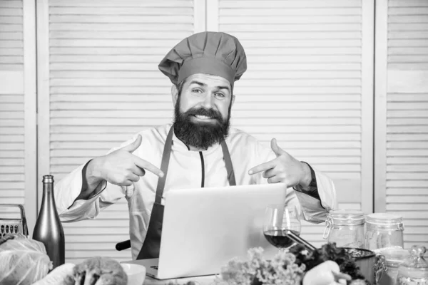 Man chef-kok op zoek naar internet recept koken voedsel. Elearning concept. Chef laptop leest culinaire recepten. Culinaire school. Hipster in hoed en schort leren hoe om online te koken. Culinair onderwijs online — Stockfoto