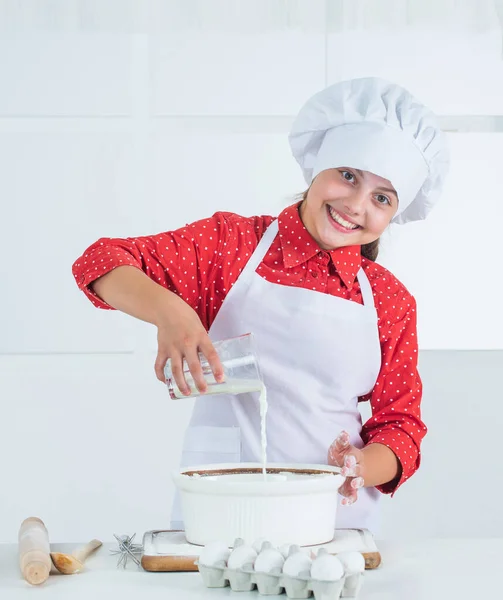 요리사 복장을 하고 요리하고 굽고 부엌에서 웃고 있는 10 대 소녀 — 스톡 사진