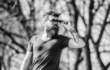 Güneş gözlüklü, sakallı, doğa geçmişi olan bir adam. Hippi koyu güneş gözlüklerine güveniyor. UV filtresi. Sakallı hippi vahşi adam koruyucu güneş gözlüğü takıyor. Sakallı adam modern güneş gözlüğü takıyor.